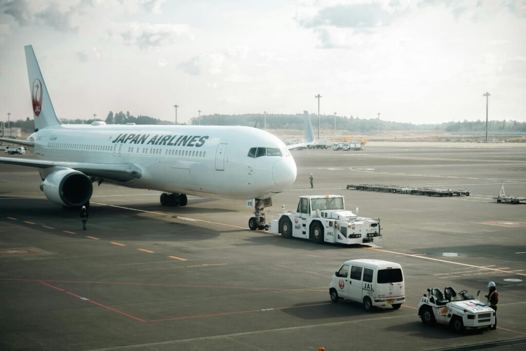 Japan Airlines aircraft stationed on the tarmac in Tokyo with ground crew vehicles.